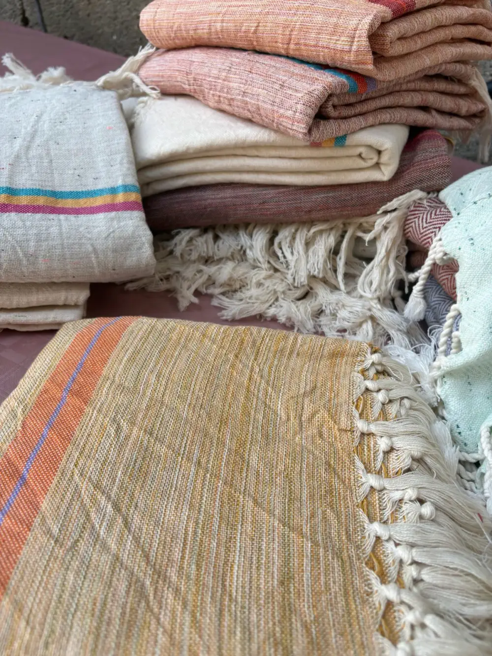 Stack of folded Turkish peshtemal towels in 100% cotton and cotton-linen blend with tasseled fringe, made in Türkiye